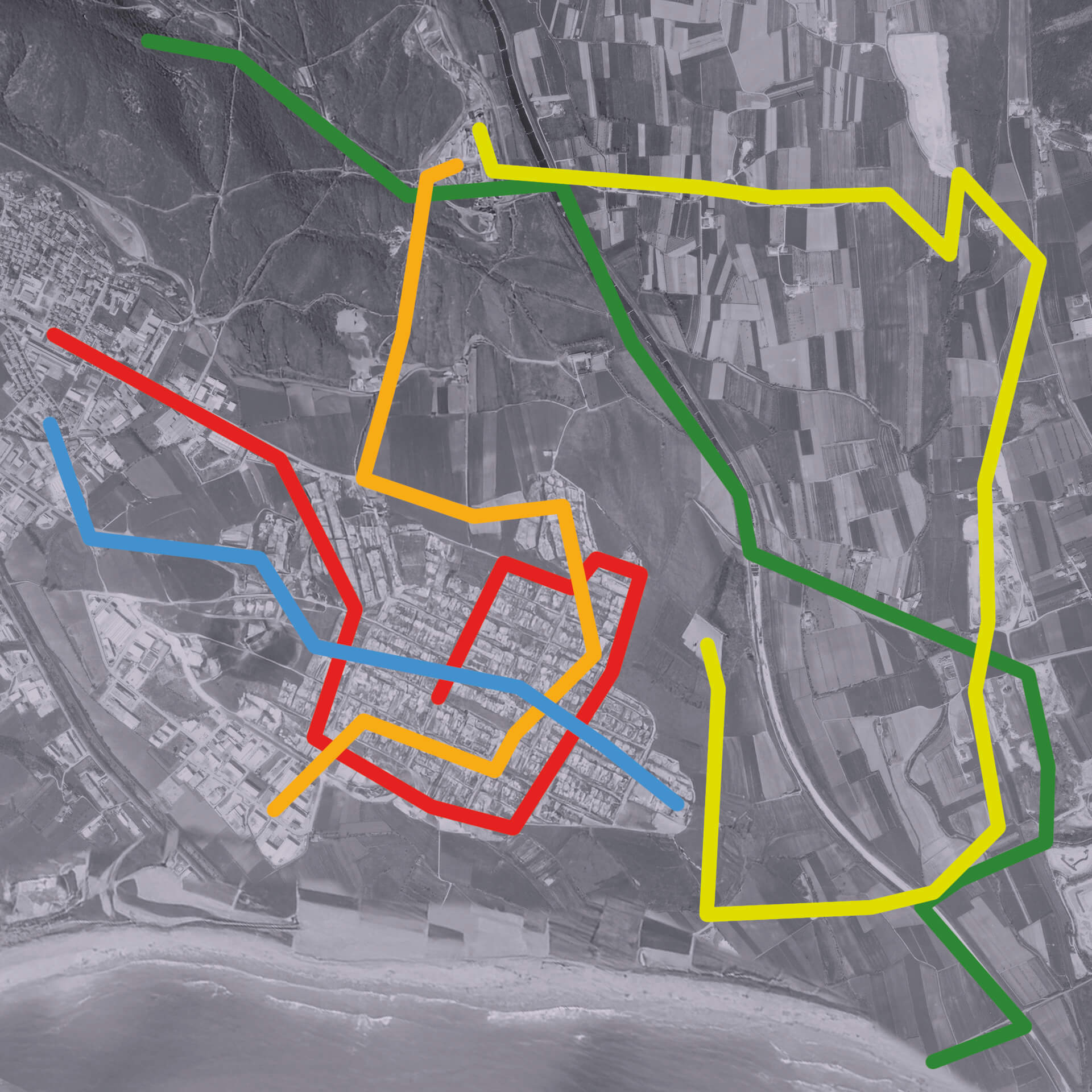 Mappa satellitare in bianco e nero di una cittadina costiera con cinque itinerari sensoriali: quadrilatero rosso nel centro storico, anello arancione interno, percorso blu da ovest a est, traccia verde in collina e giro giallo rurale fino alla costa.